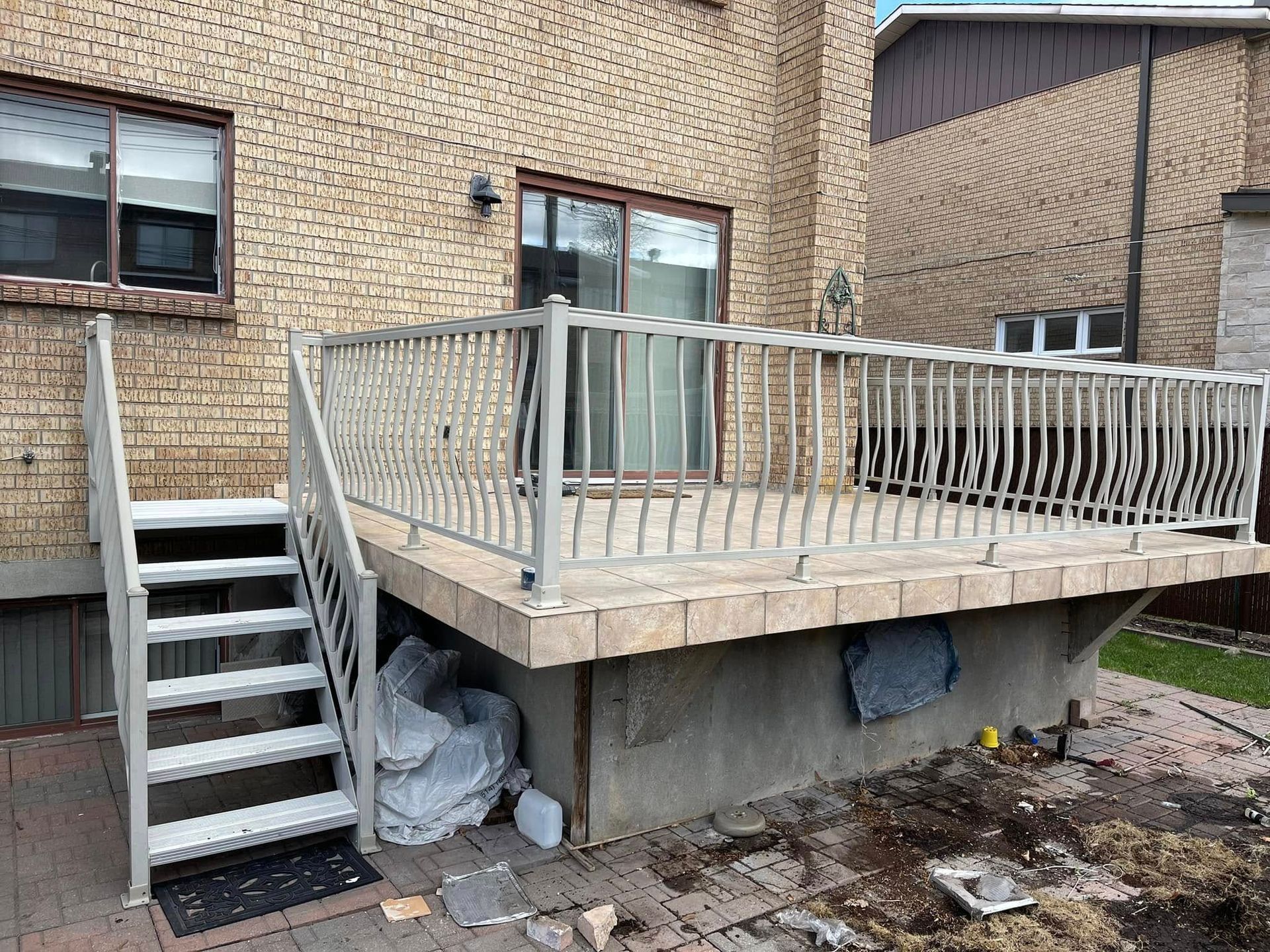 Bâtiment en briques avec terrasse et escalier en bois patinés par le temps, laissant apparaître la charpente et des débris en dessous.