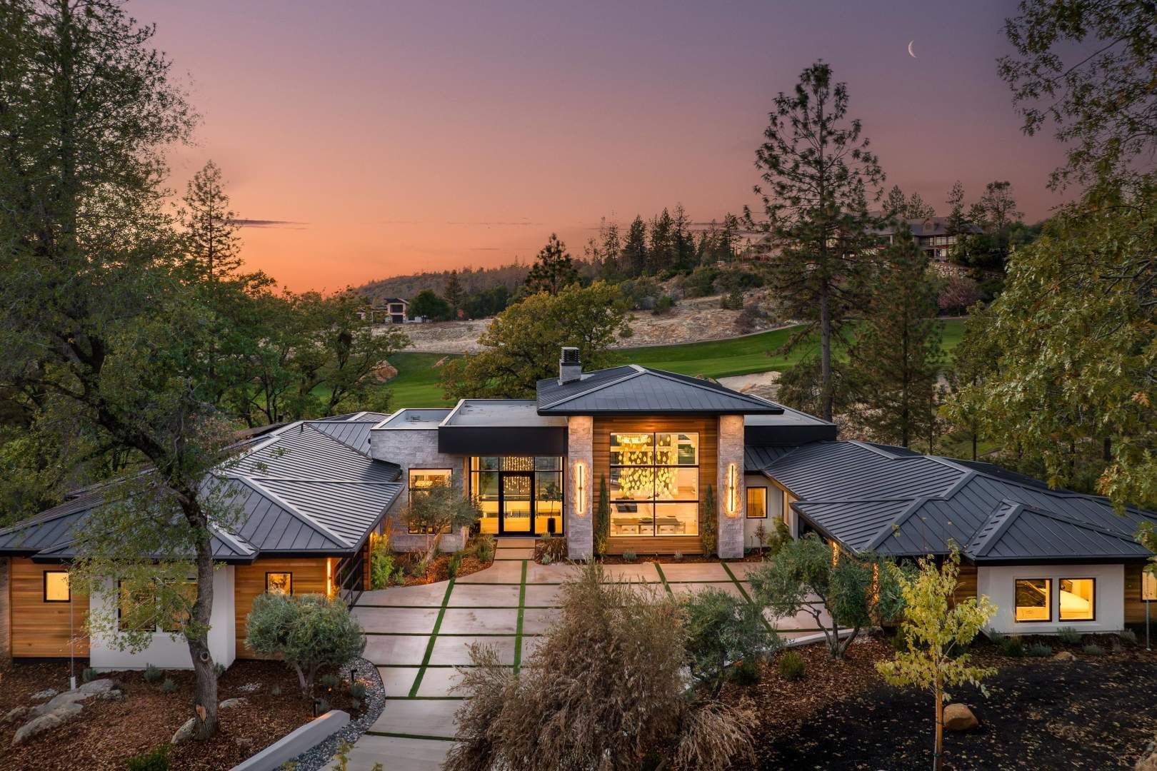 Evening view of one of the luxury homes in Meadow Vista, CA featuring modern architecture and native landscaping.