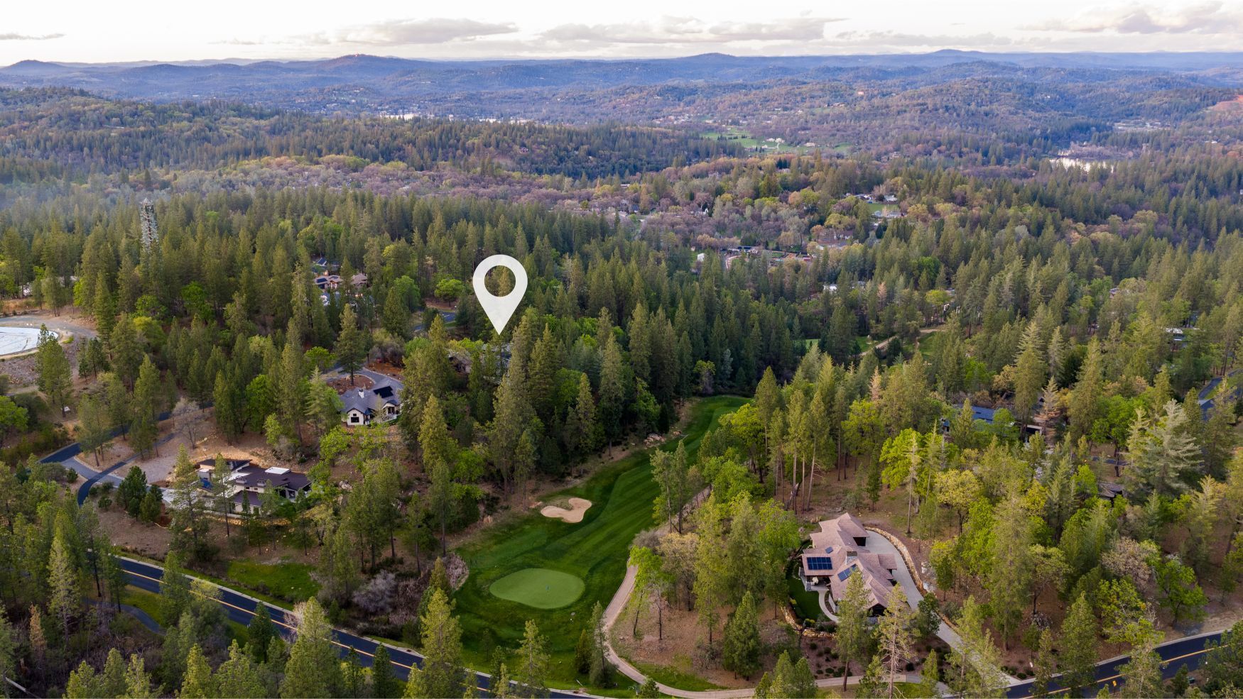  Aerial view of 1632 The Point Road showing location pin pine forest golf course fairway and mountain backdrop.
