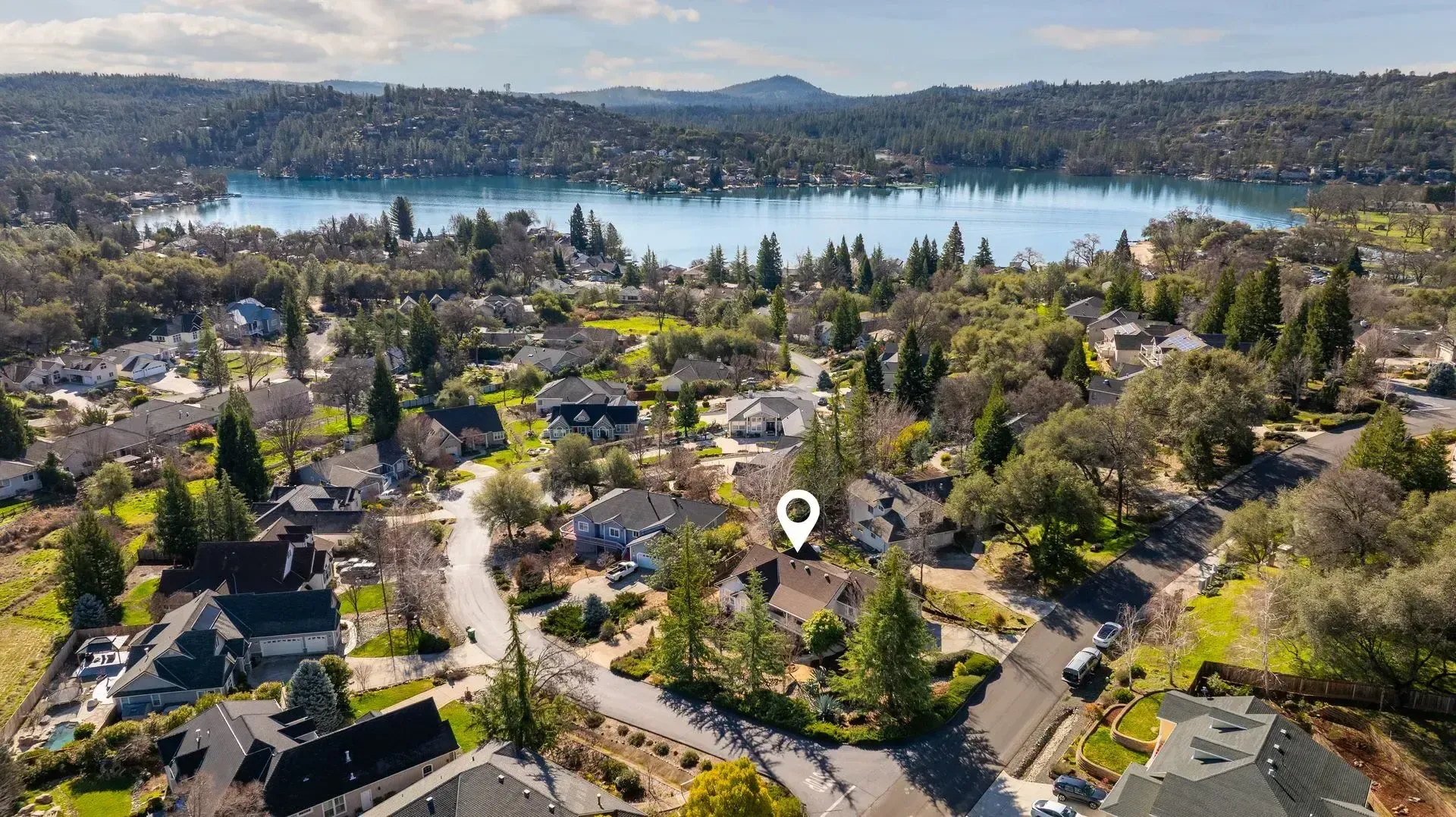 An aerial view shows a house with a scenic lake, highlighting country properties in Penny Valley, CA.