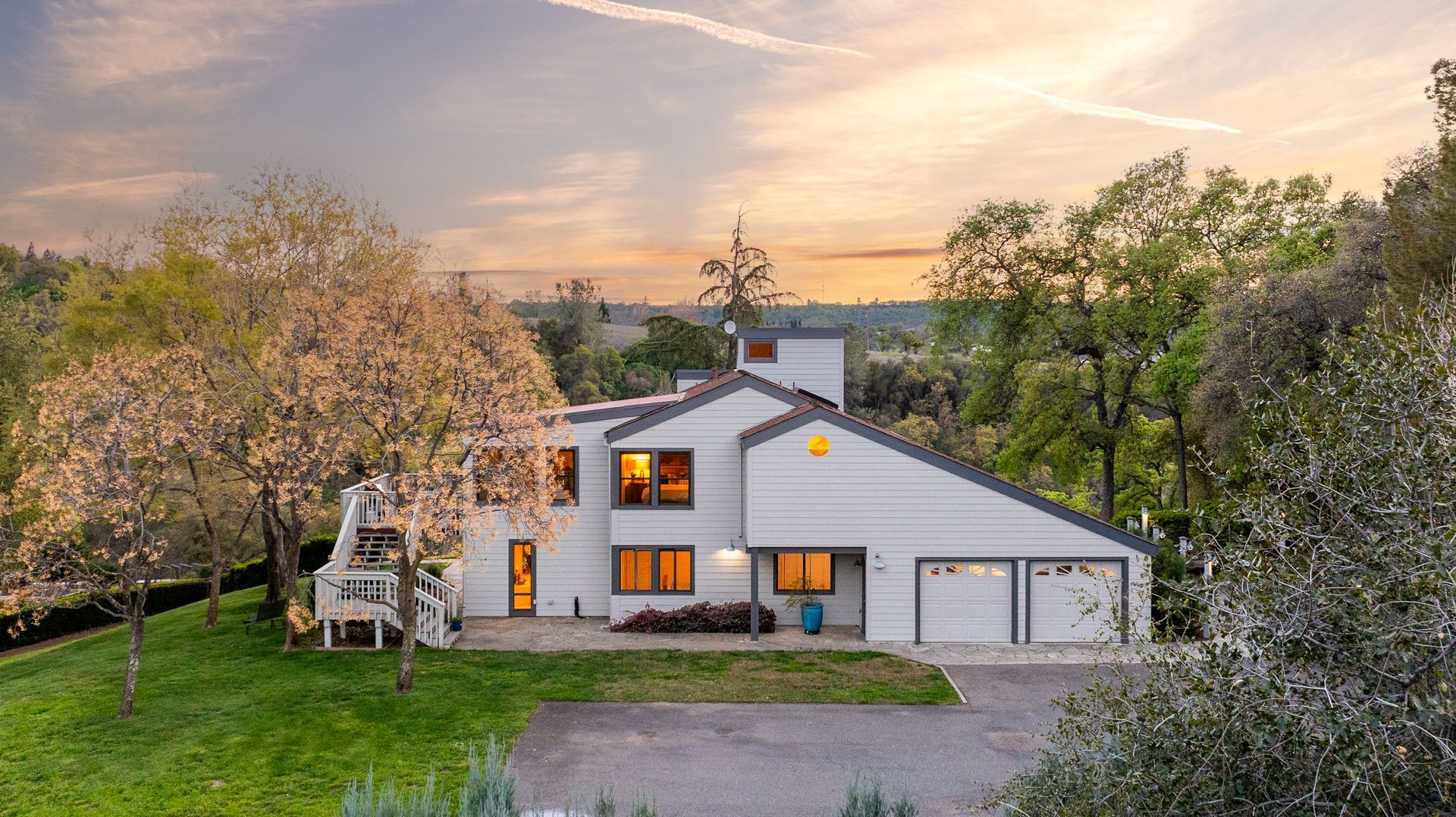 Charming modern home at dusk with professional landscaping and inviting interior lighting.