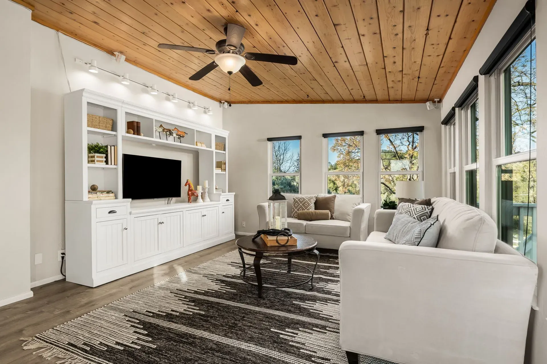 Bright living room interior with wood-paneled ceiling, large windows, and modern furnishings.
