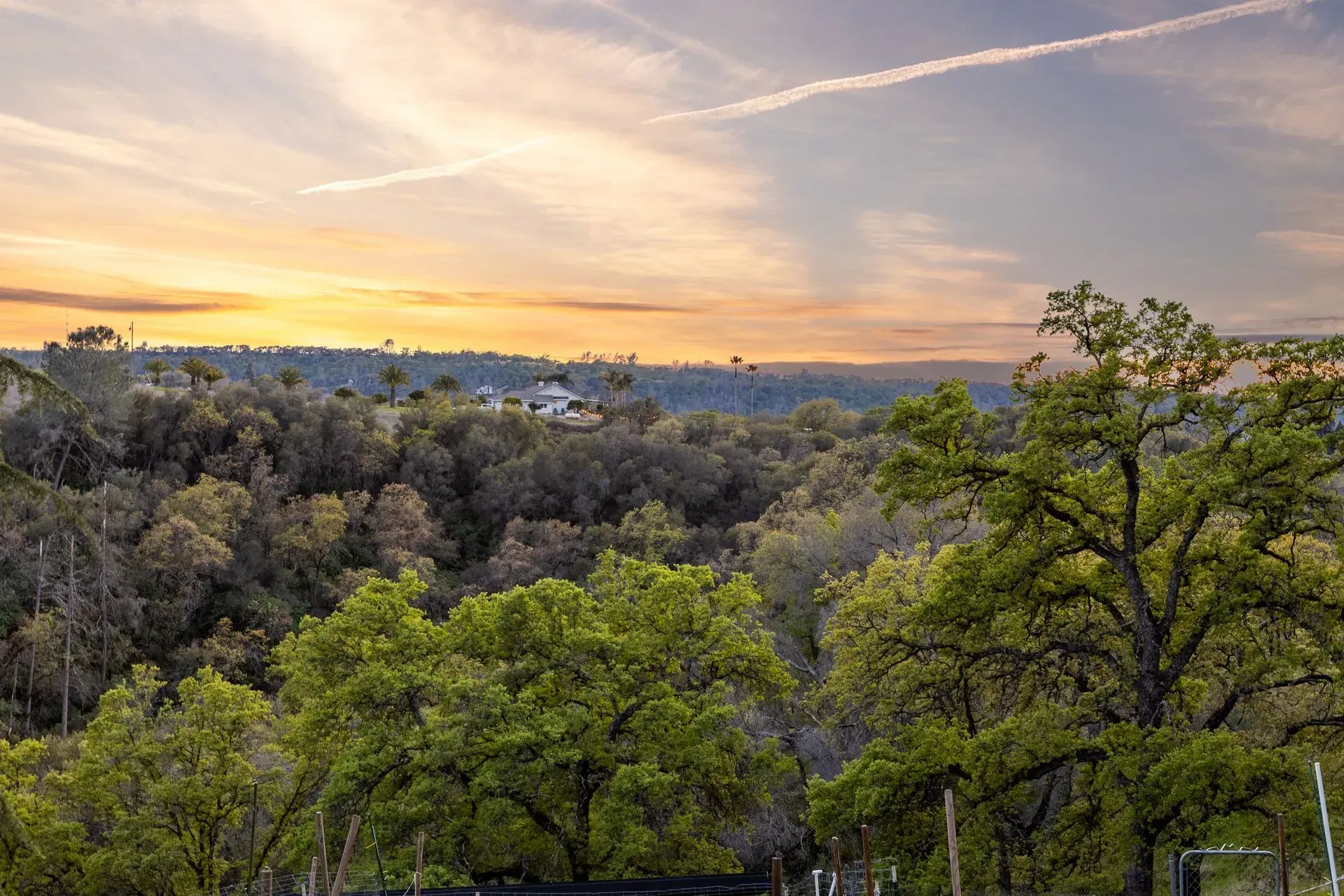 Golden hour view of rolling hills and open land beneath a vivid sunset sky.
