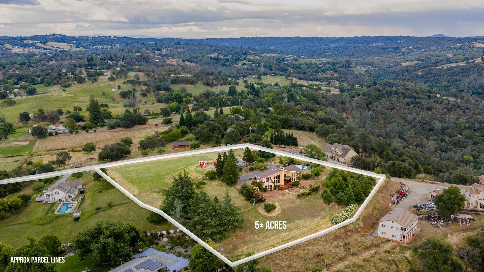Aerial view of a 5-plus acre parcel with home and mature trees overlooking rolling valley with property boundary lines marked