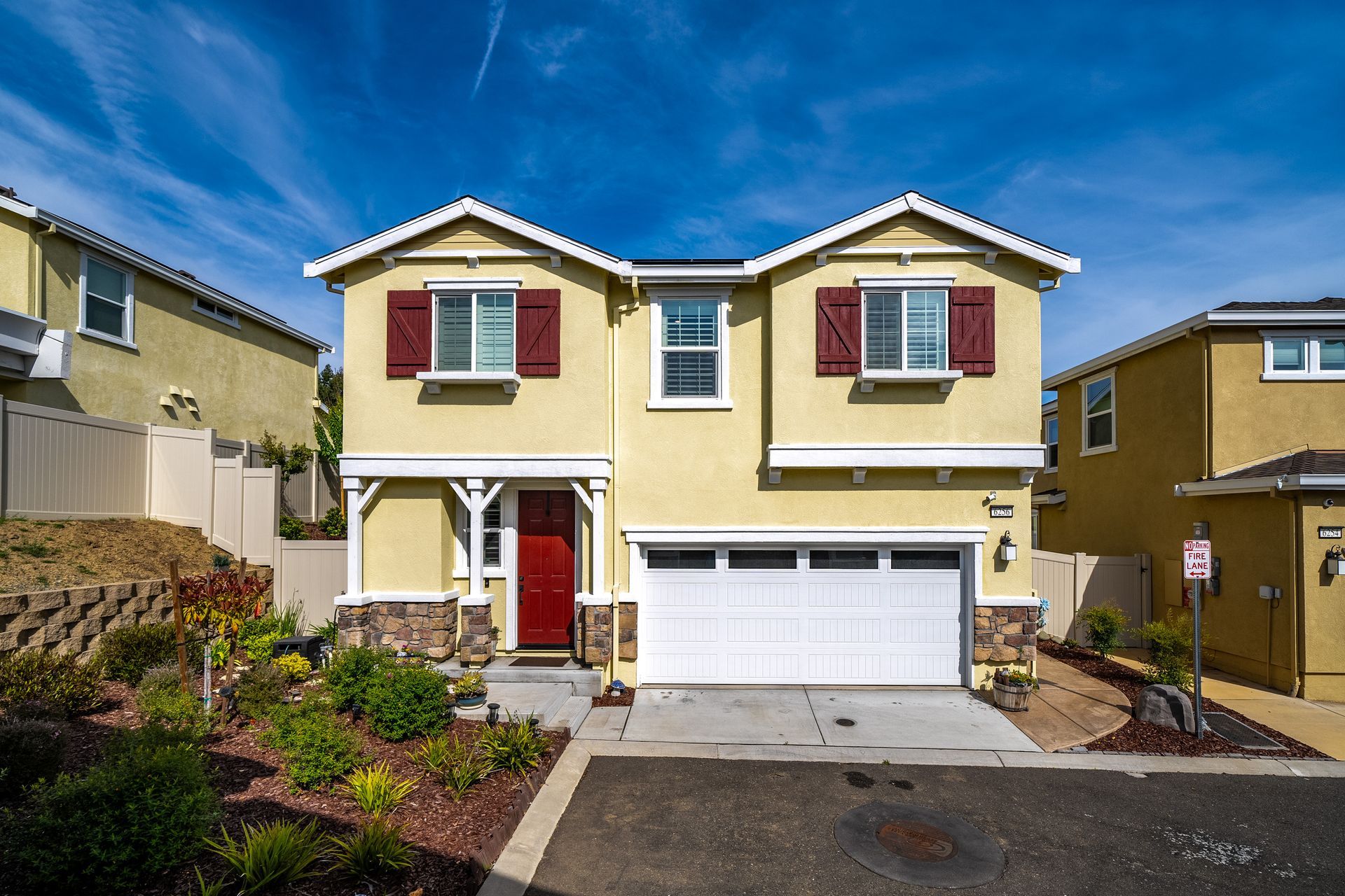 Two-story home with red shutters, landscaped yard, and garage, listed by Nicole Spencer—GUIDE Real Estate.