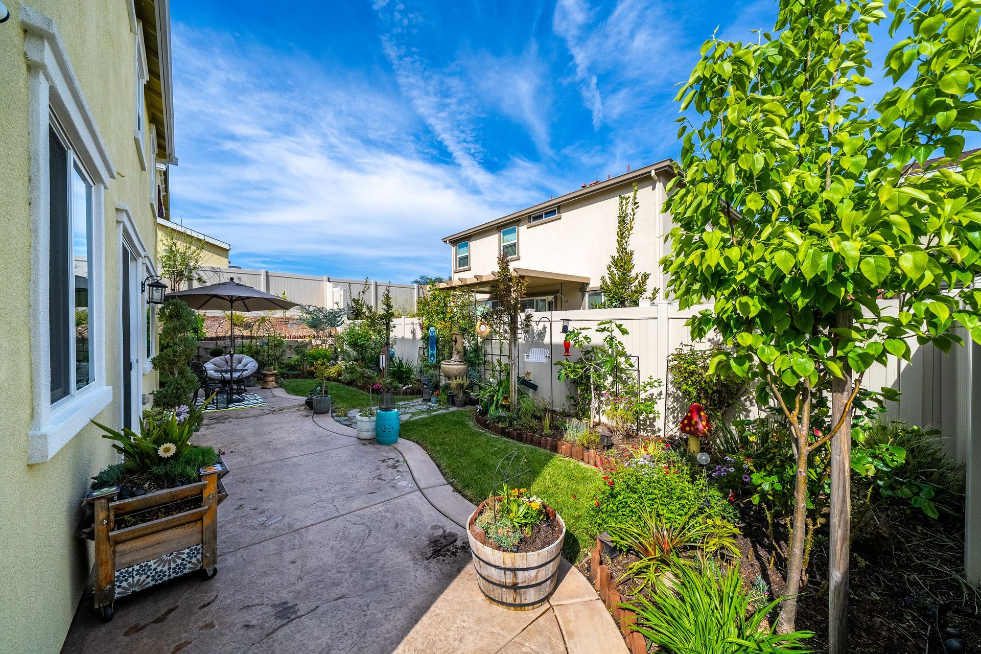 Peaceful backyard retreat with mature trees, paved path, and garden space behind a Citrus Heights country-style home.