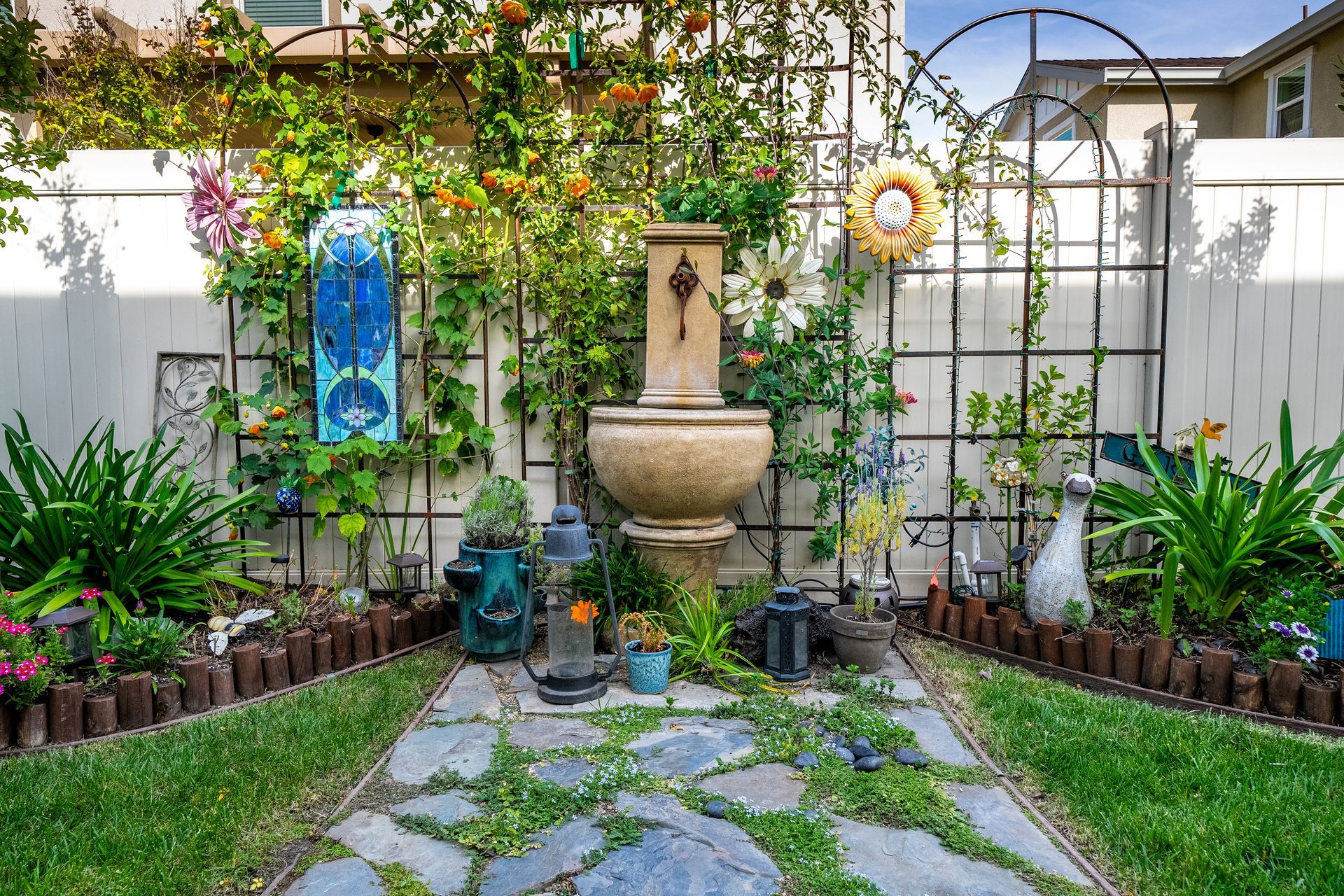 Serene backyard garden with stone fountain, decorative trellis, and mature plants styled for real estate visuals.