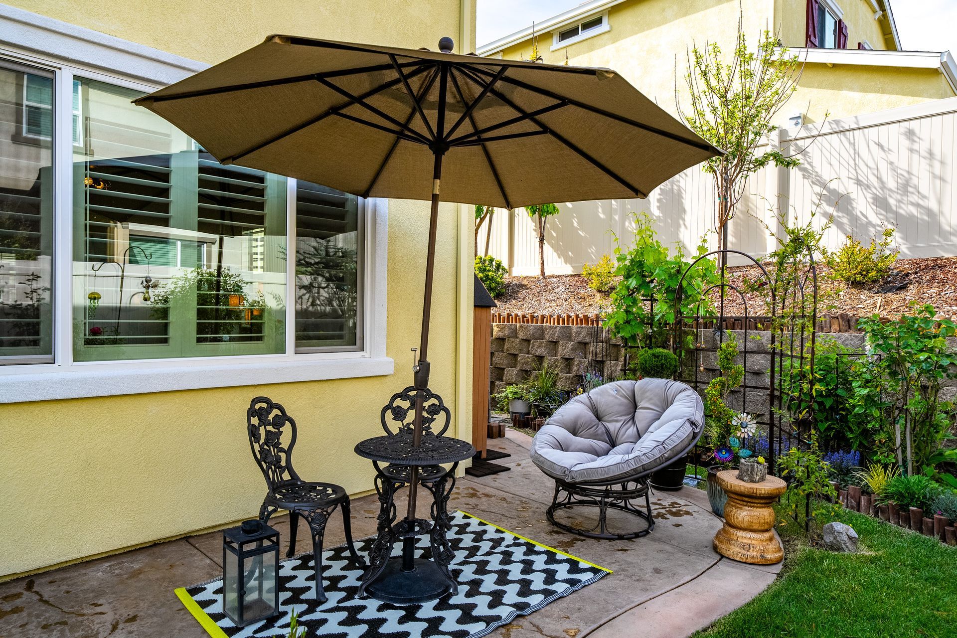 Covered patio with umbrella and lounge setup, used in real estate marketing to showcase outdoor living spaces.