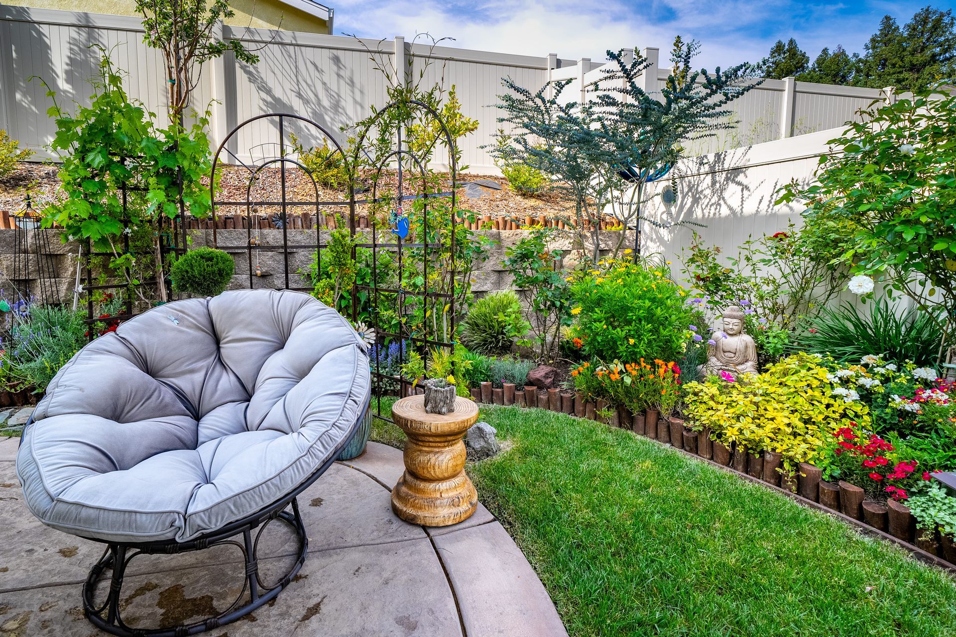 Backyard garden with a cozy lounge chair, vibrant flowers, and a private seating area for relaxing or entertaining.