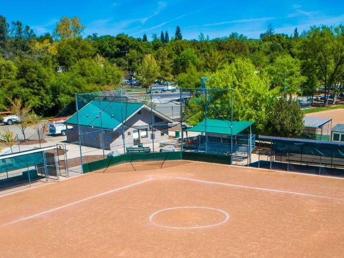 Aerial view of a Granite Bay property with a sport court surrounded by mature trees.
