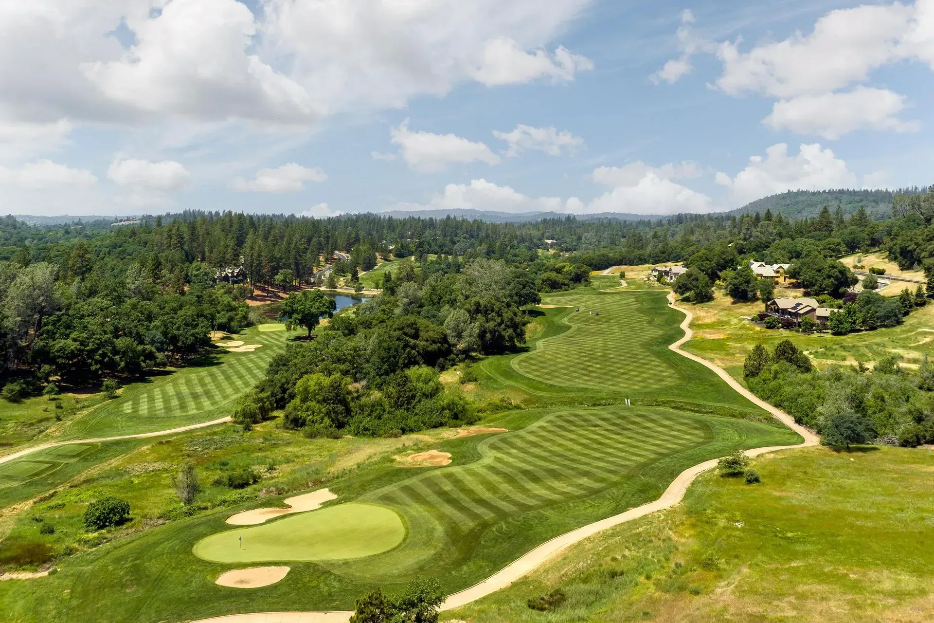 Aerial view of a golf course community with rolling hills and manicured green fairways.