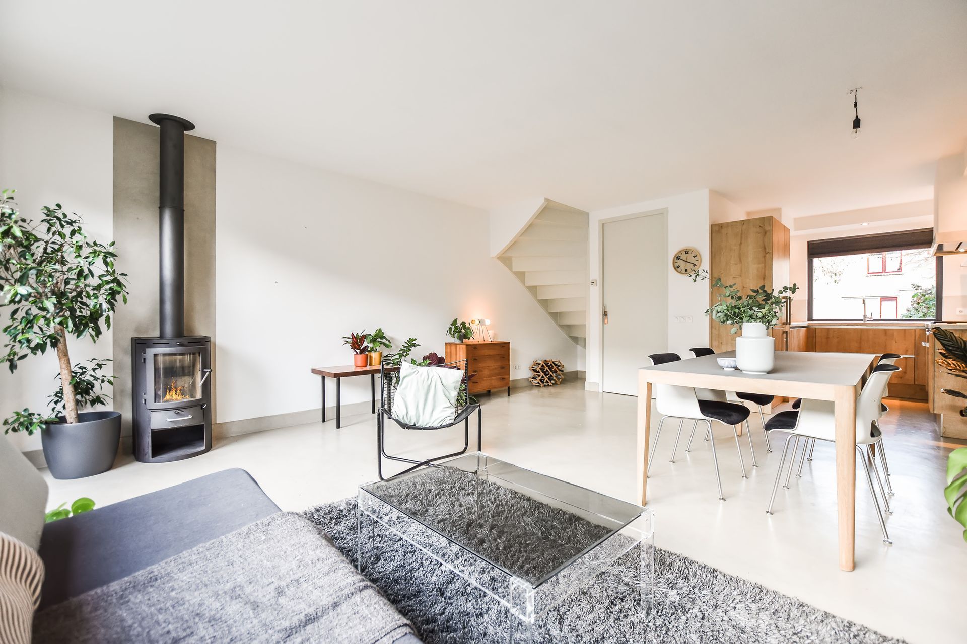 Bright open-plan living and dining area with a staircase, large windows, and modern finishes.