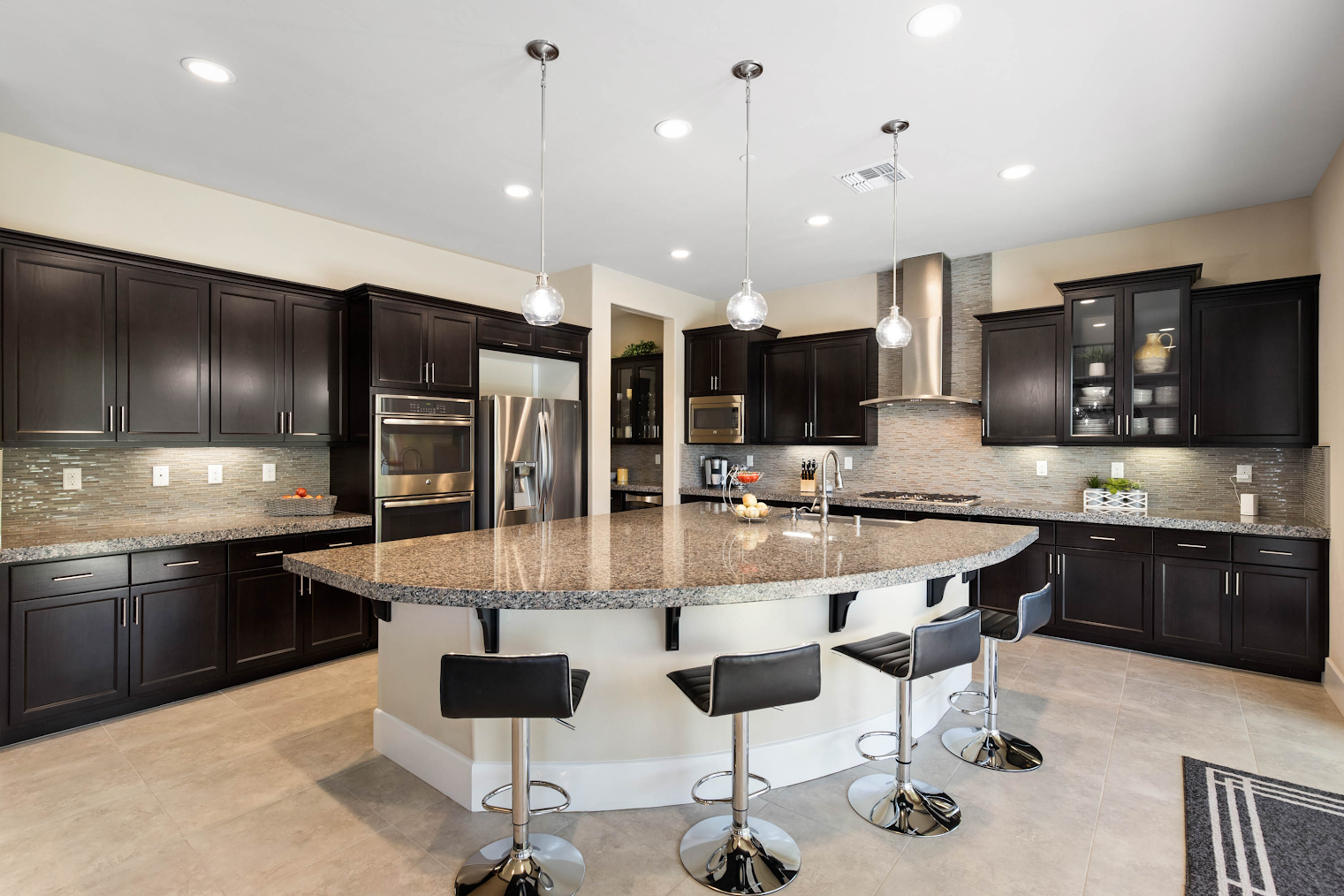 Modern kitchen with dark cabinetry, large island with bar seating, and pendant lighting.
