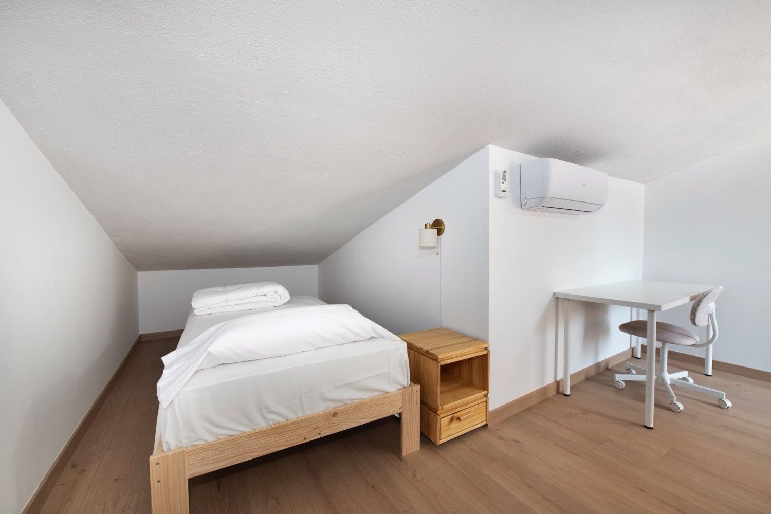 Sala de estar con sofá y cortinas transparentes junto a una puerta que da al balcón, con vistas luminosas a la ciudad.