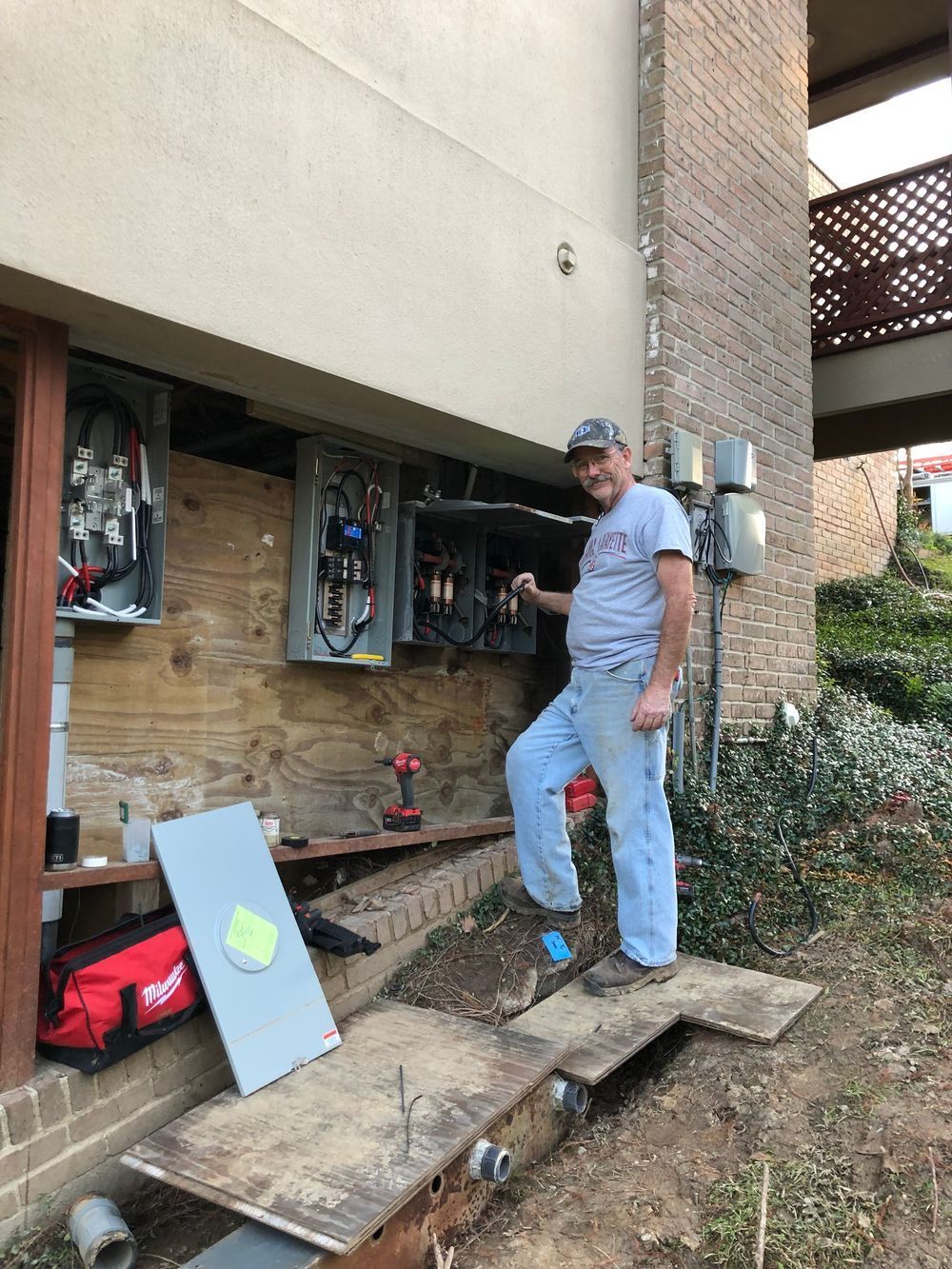 A man is standing in front of a brick building.