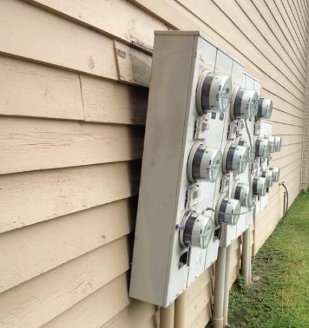 A row of electrical boxes on the side of a house