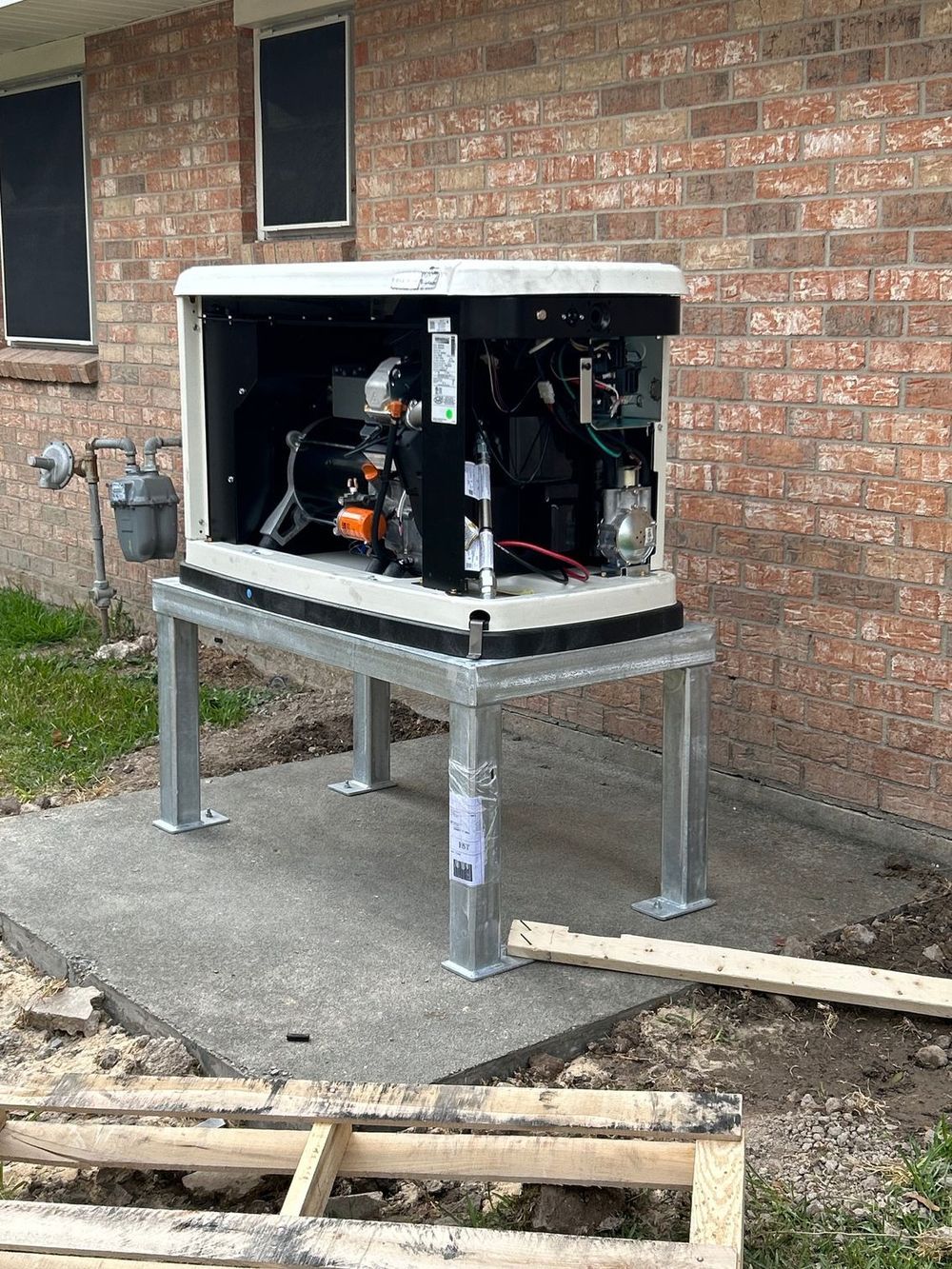 A generator is sitting on a metal stand in front of a brick building.