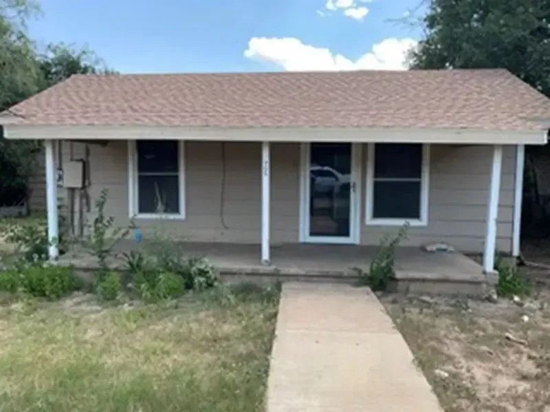 Small beige house with a front porch, white columns, and a walkway leading to the door.