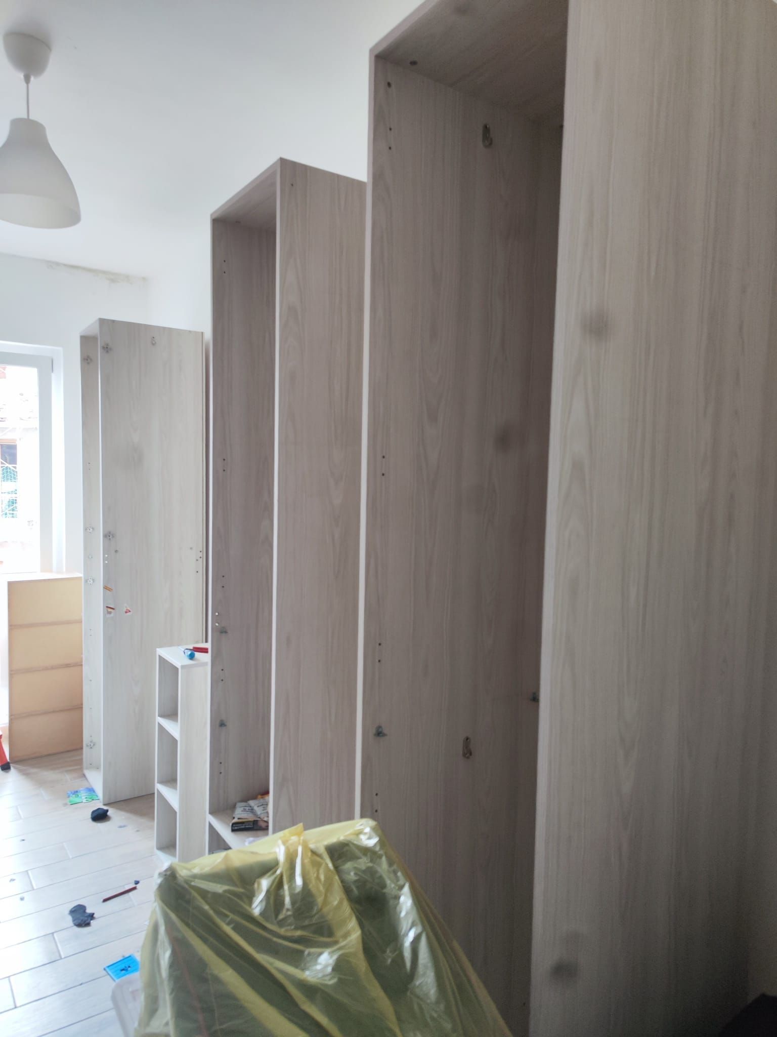 Stanza stretta con alti armadi grigi lungo la parete e detriti di cantiere sul pavimento.