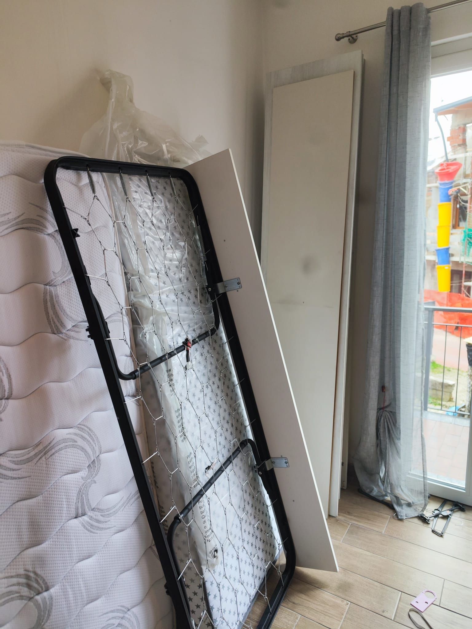 Materasso e porte a battente in un corridoio accanto a una porta luminosa e aperta