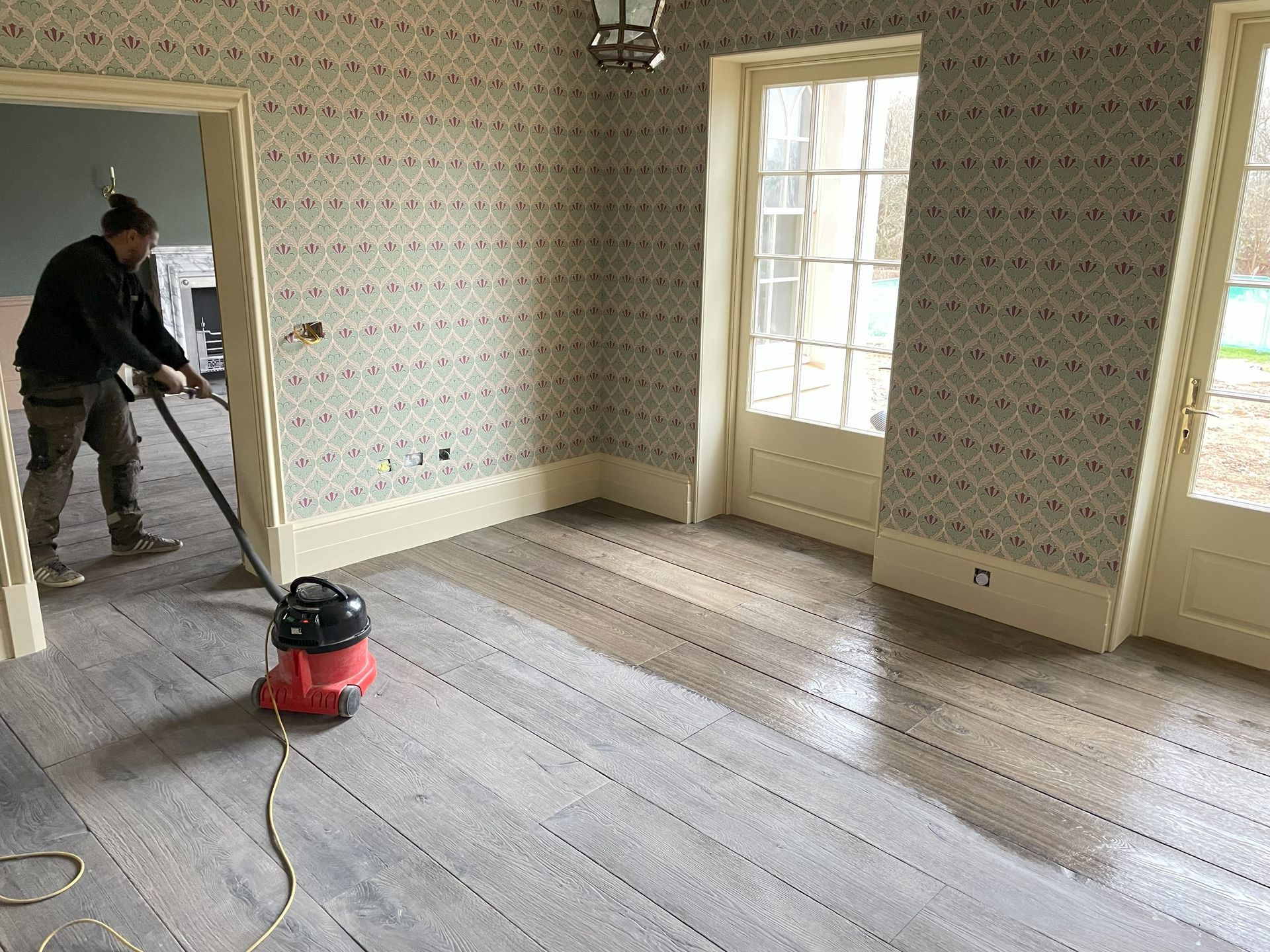 Dyfed Richards employee with a Henry Hoover, vacuuming before applying timber flooring finish