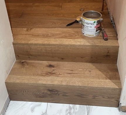 A can of paint is sitting on top of a wooden staircase.