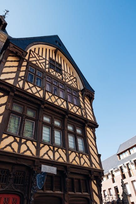 Timber-framed building with dark wood and cream walls, under blue sky.