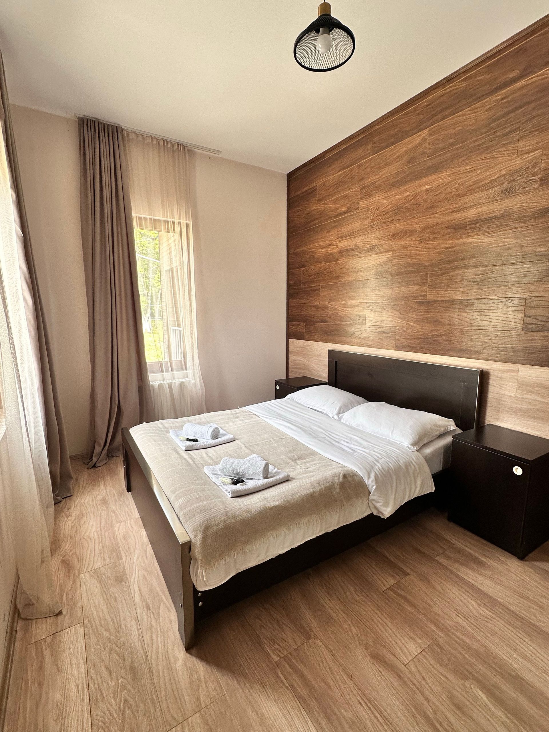 Person opening a hotel room door. Bedroom with bed and curtains in the background.