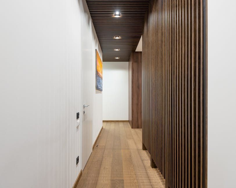 Narrow hallway with wood flooring, white walls, and a wooden slat wall.