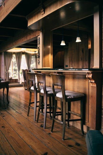 Wooden bar with stools. Pendent lights and windows in the background.