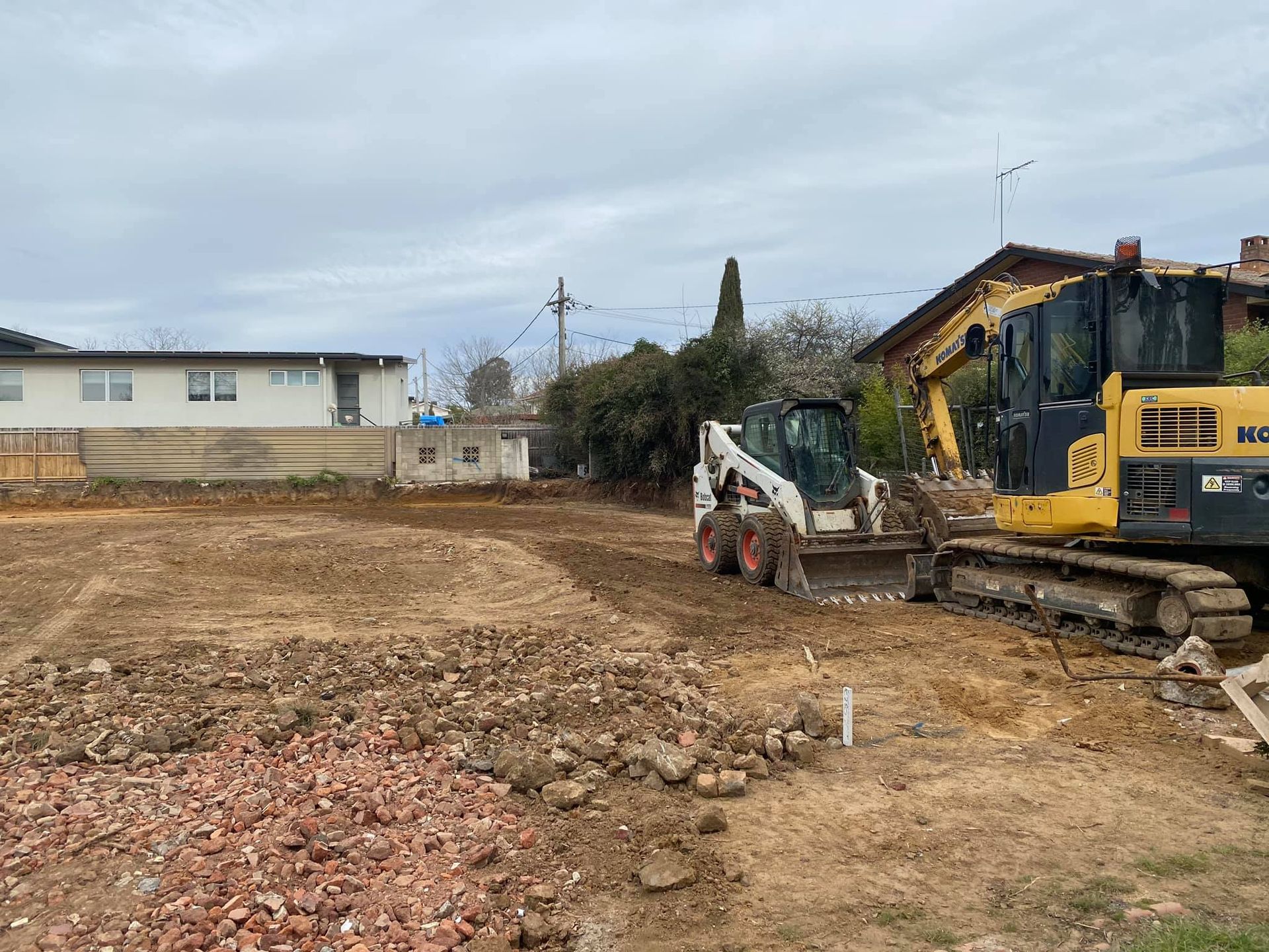 Construction site with a skid steer and excavator clearing a lot. — Brucic Construction in Dickson, ACT