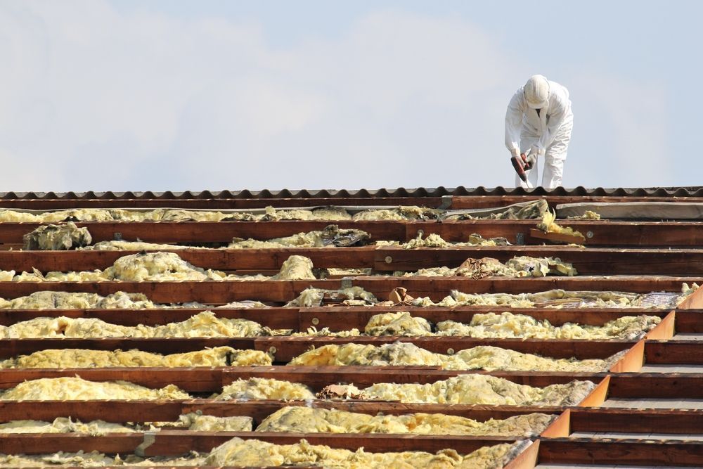 Person in White Protective Suit Working on a Damaged Roof — Brucic Construction in Queanbeyan, NSW