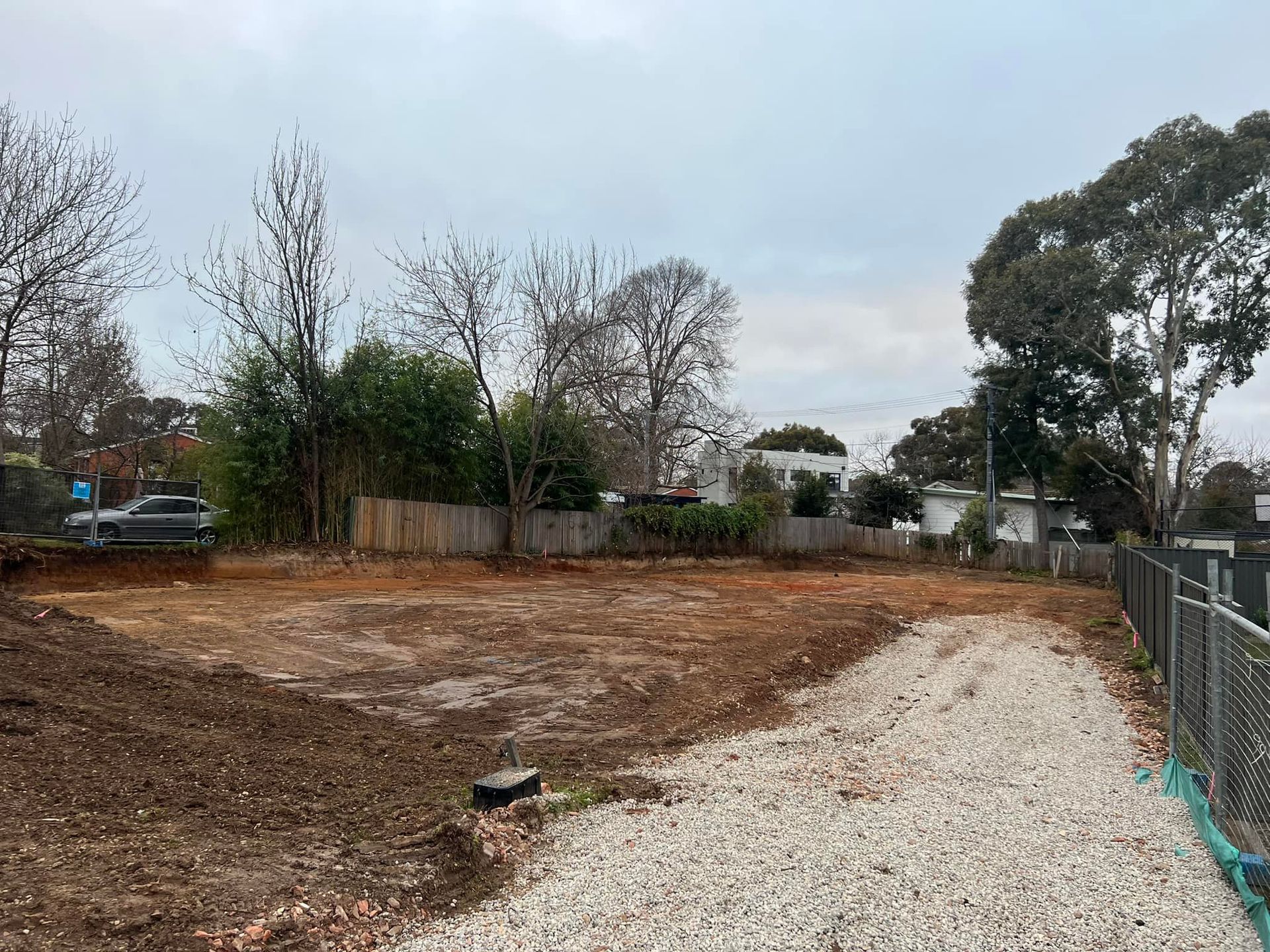 Cleared vacant lot with gravel path and fence under cloudy sky. — Brucic Construction in Dickson, ACT