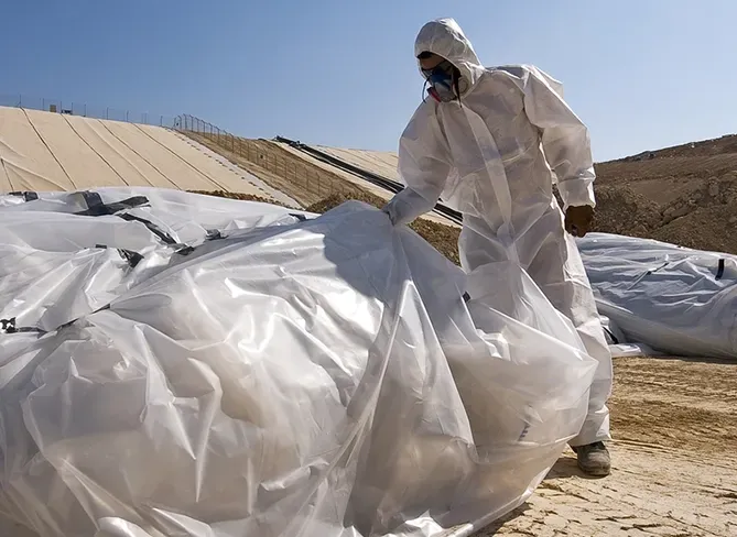 Person in Protective Bagging Asbestos on a Demolition Site— Brucic Construction in Dickson, ACT