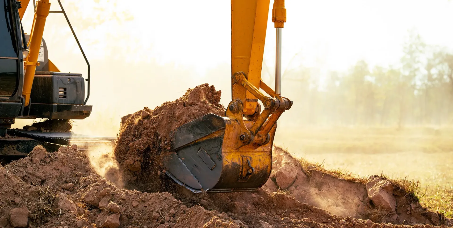 Yellow Excavator Scooping Dirt Against a Blue Sky — Brucic Construction in Queanbeyan, NSW