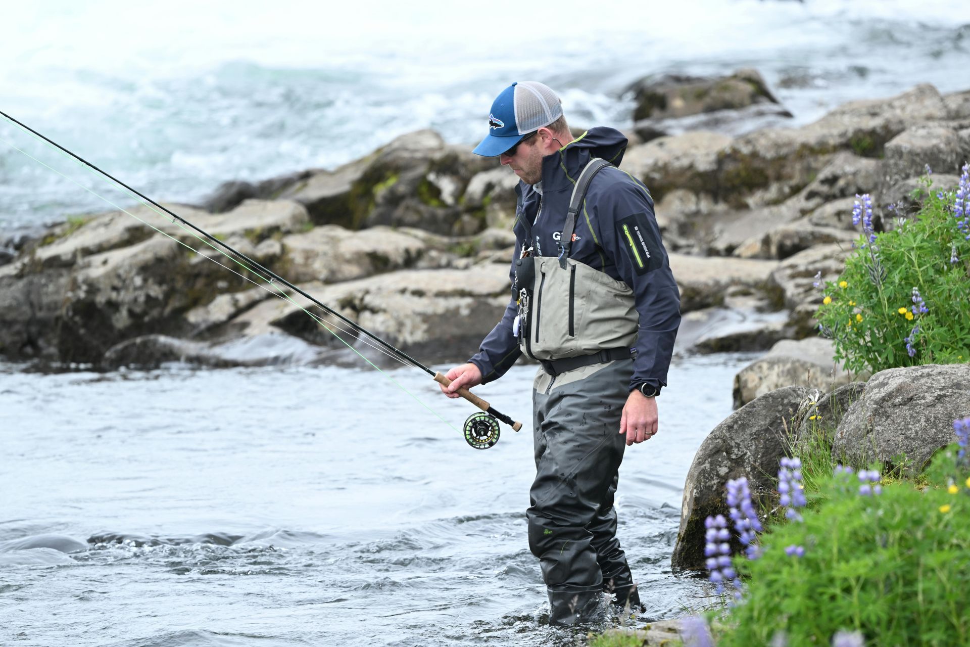 A man is fishing in a river with a fishing rod.
