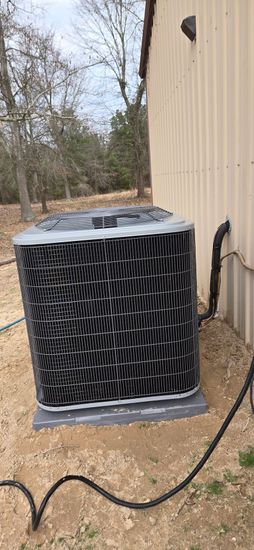 A large air conditioner is sitting outside of a building.