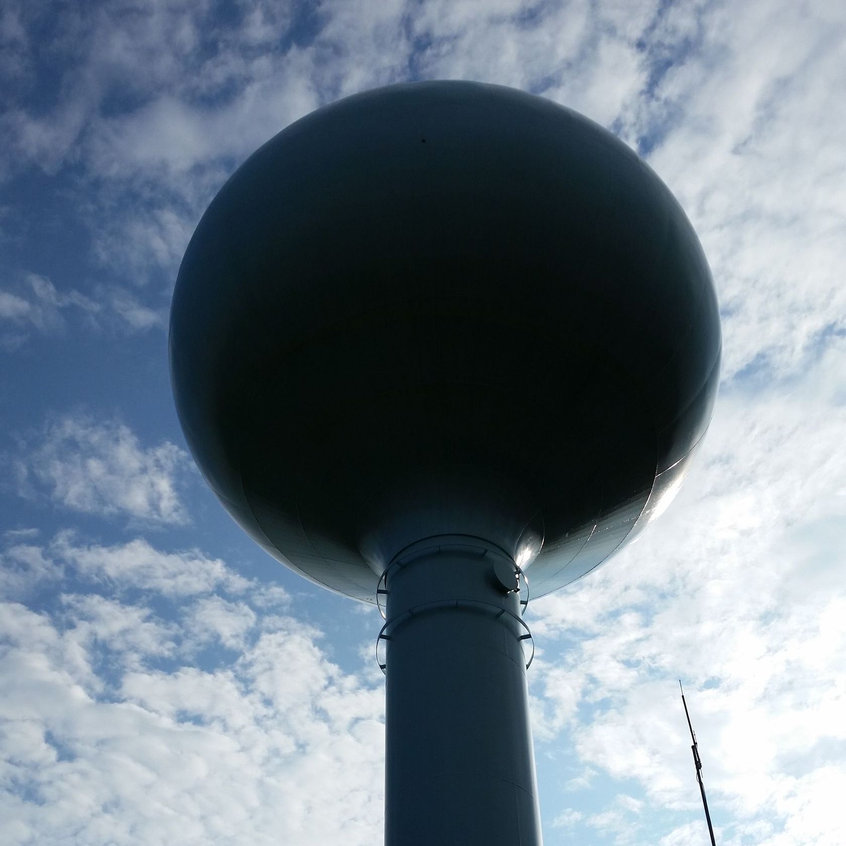 A large ball on top of a pole with a blue sky in the background