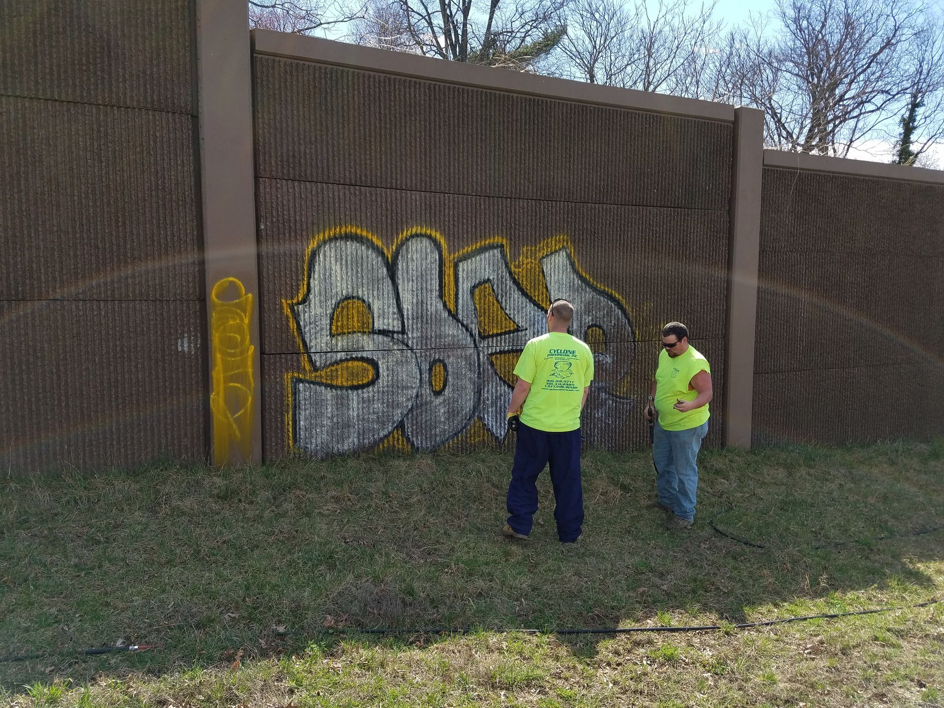 Two men are standing in front of a wall with graffiti on it.