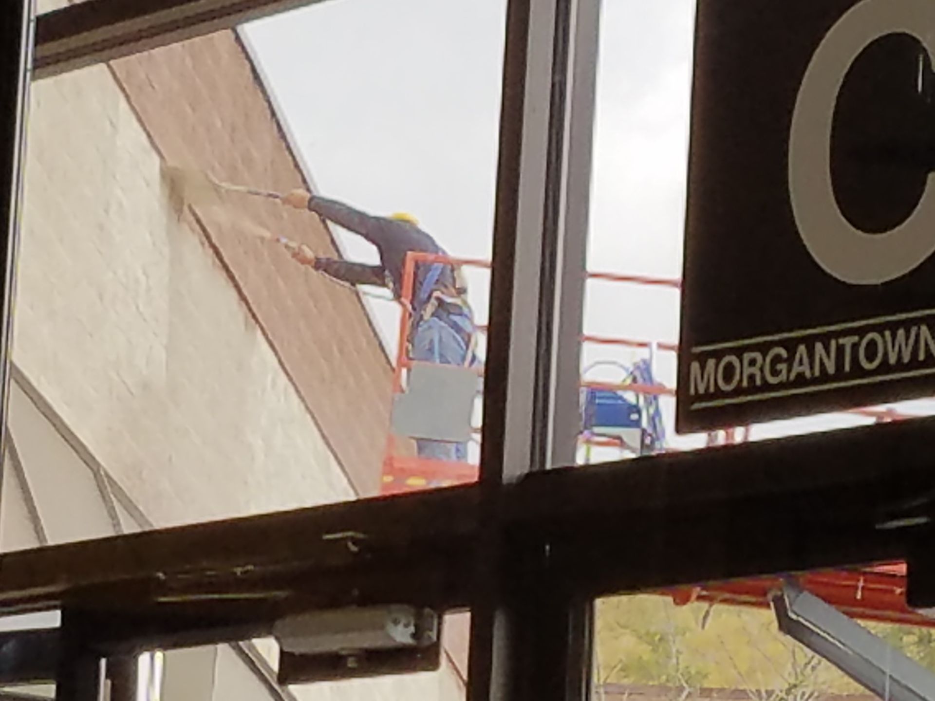 A man is painting the side of a building in morgantown