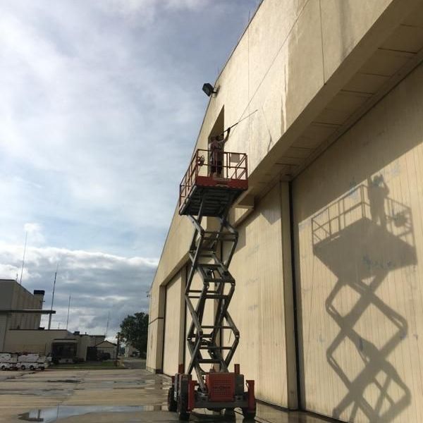 A man on a scissor lift cleaning a building