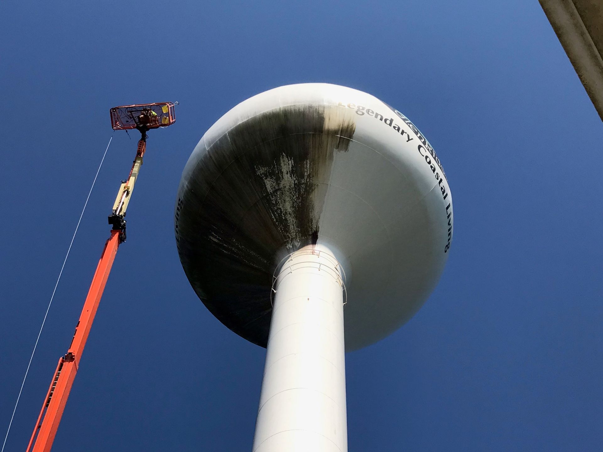 A water tower is being cleaned by a crane