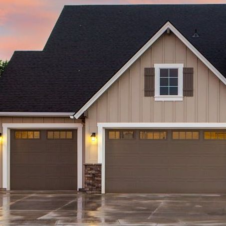 A house with two garage doors and a black roof.