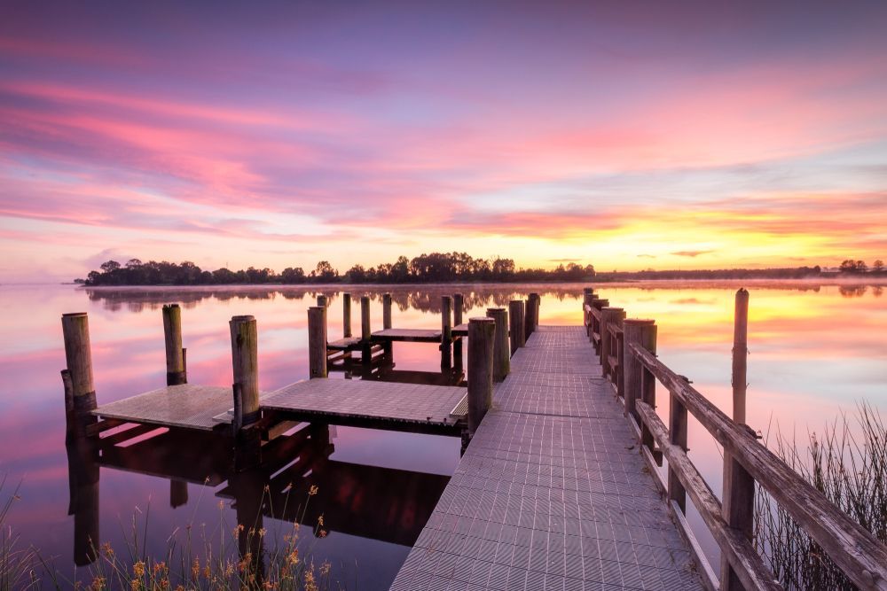 A Dock Overlooking a Lake With a Sunset in the Background — Able Building And Pest Inspections In Grafton, NSW