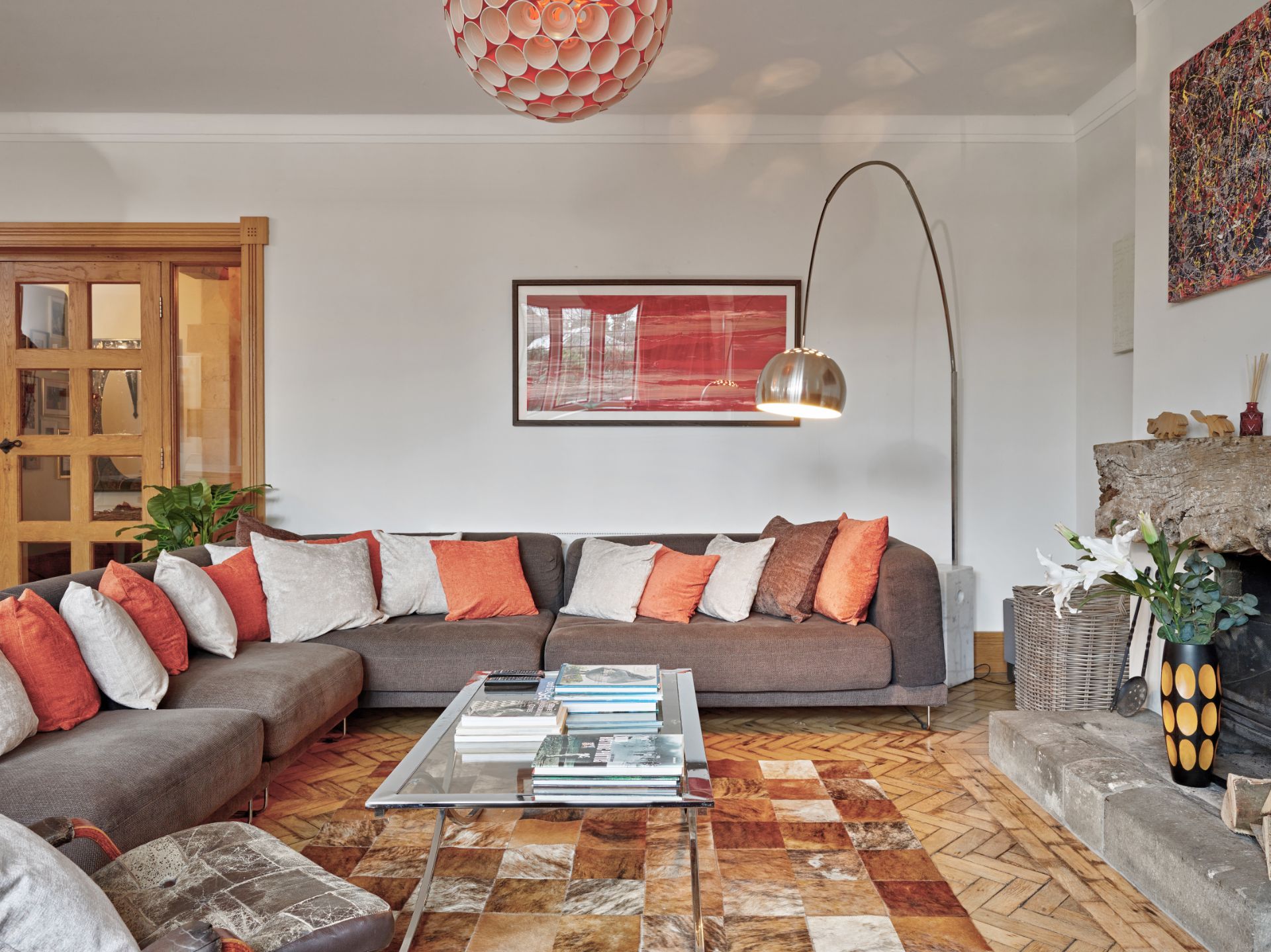 Modern living room with gray sectional, orange pillows, patterned rug, and arc floor lamp
