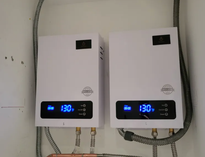 Two water heaters are hanging on a wall and one of them says 130 degrees