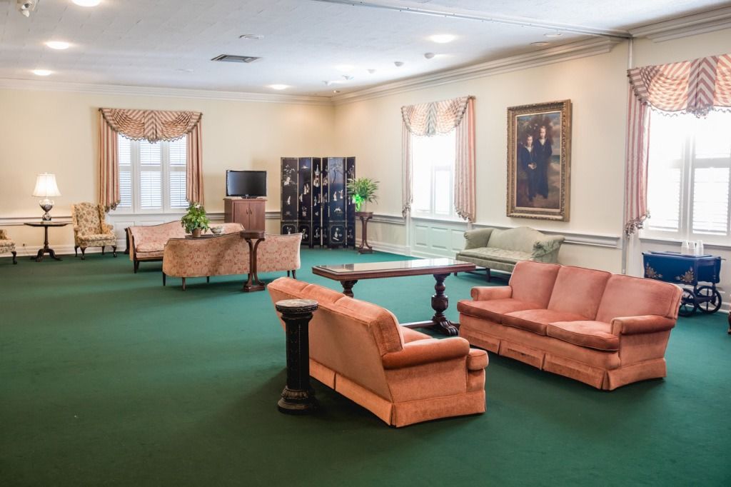 Large lounge with green carpet, peach sofas, and a dark wood table.