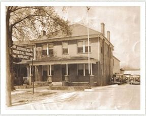 Jernigan Funeral Home and Ambulance building. Sign on corner. Several parked vehicles. Sepia-toned photograph.