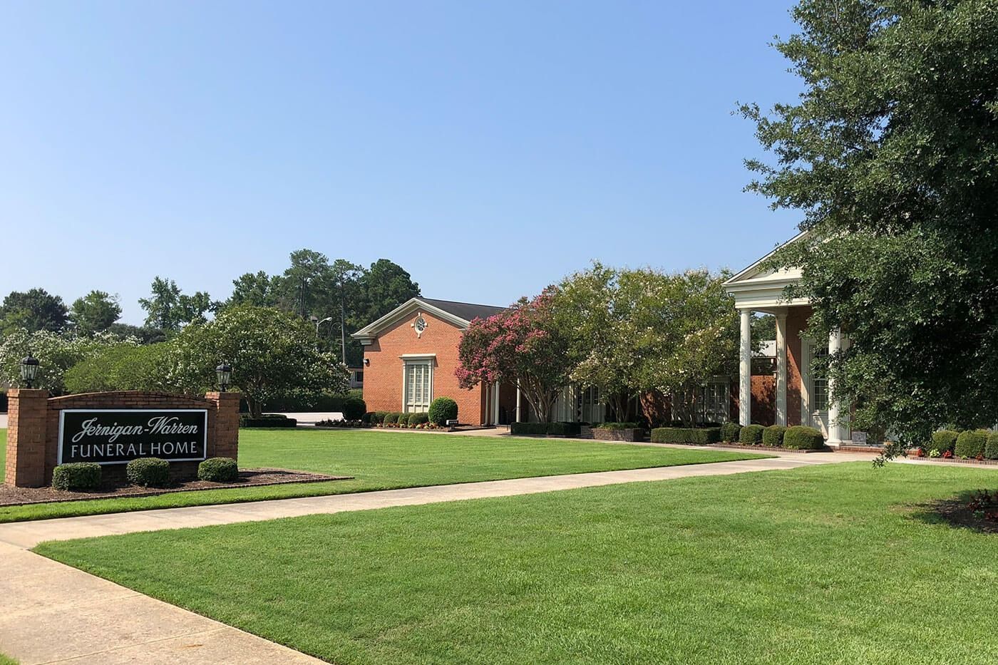 Sign for Jameson Pointe subdivision with brick buildings and manicured lawn.