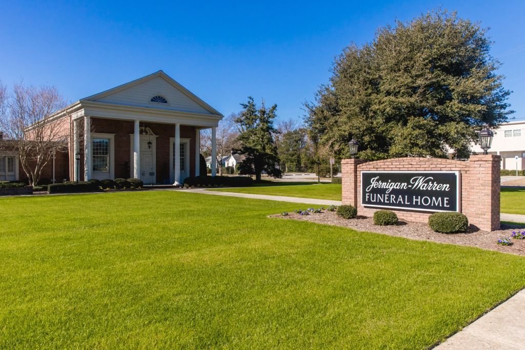 Exterior of a brick building with white columns and a sign reading